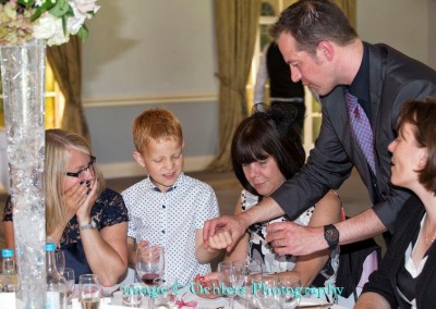 Family at wedding table amazed by magician trick